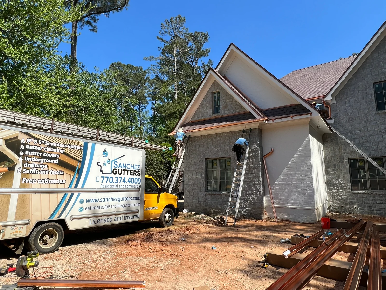 Seamless copper gutter and fascia installation on stone residential home with ladder access